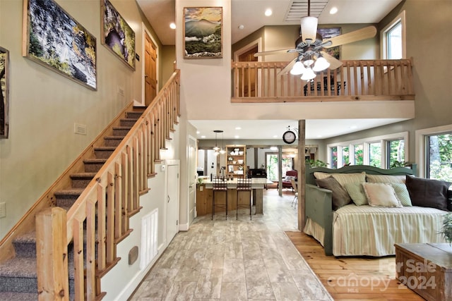 interior space with light hardwood / wood-style flooring, a high ceiling, and ceiling fan