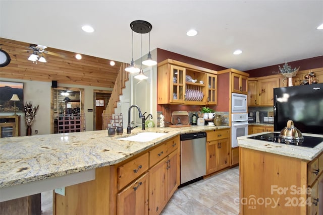 kitchen featuring hanging light fixtures, light stone countertops, black appliances, ceiling fan, and sink