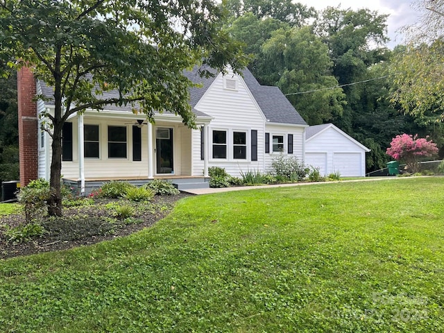 view of front of property with a front lawn, central AC unit, an outbuilding, a garage, and covered porch