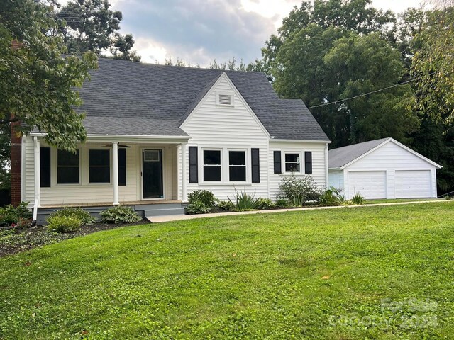 view of front of house with covered porch, an outbuilding, a front yard, and a garage