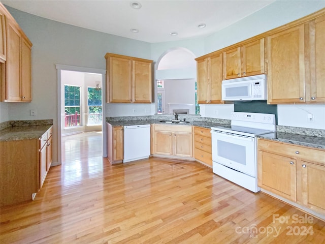 kitchen featuring dark stone countertops, white appliances, sink, and light hardwood / wood-style floors