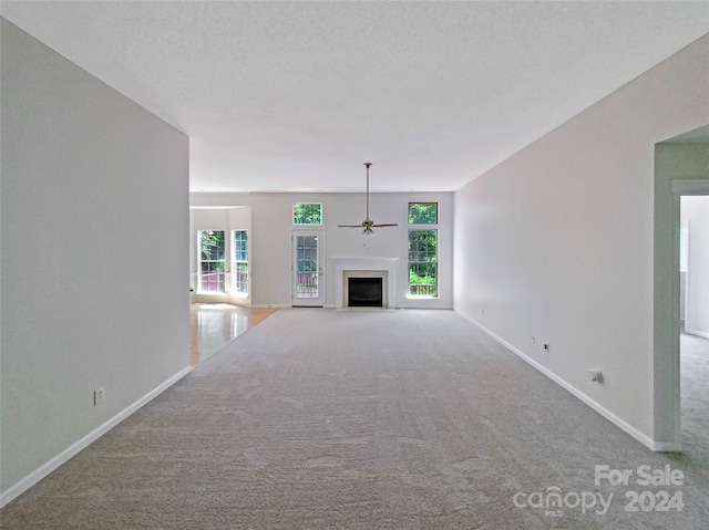 unfurnished living room with baseboards, carpet floors, a fireplace, and a healthy amount of sunlight