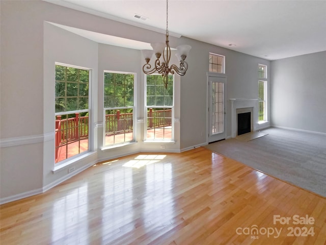 unfurnished living room with visible vents, an inviting chandelier, a fireplace with flush hearth, wood finished floors, and baseboards