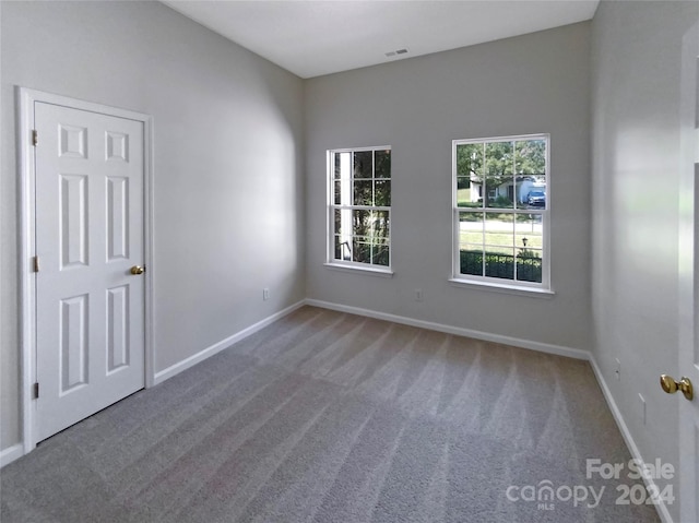 unfurnished room featuring baseboards, visible vents, and carpet flooring