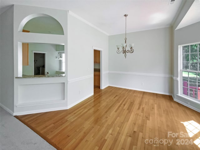 spare room featuring a notable chandelier, baseboards, and wood finished floors