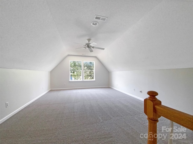 additional living space with ceiling fan, carpet, a textured ceiling, and vaulted ceiling