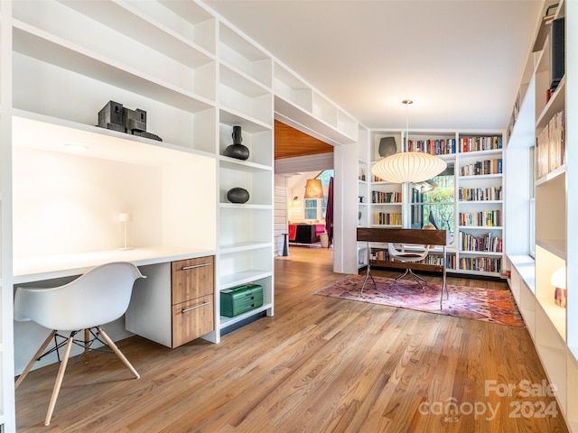 home office with built in desk and light hardwood / wood-style floors