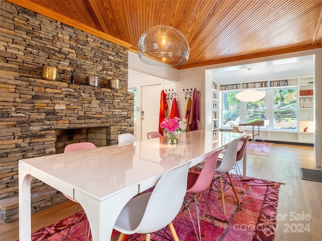 dining room featuring hardwood / wood-style floors, crown molding, wood ceiling, and a fireplace