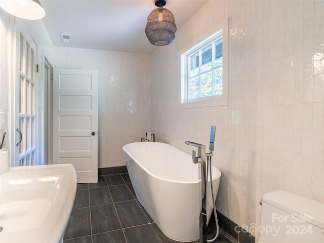 bathroom with tile walls, toilet, a tub, and tile patterned floors