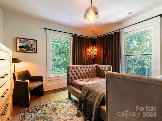 bedroom with light hardwood / wood-style floors and an inviting chandelier