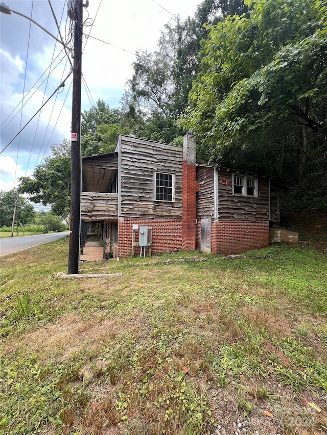 view of home's exterior with brick siding and a lawn