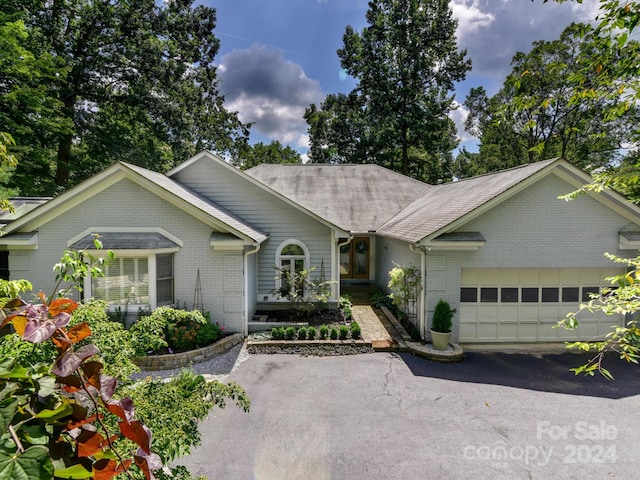 ranch-style home featuring aphalt driveway, brick siding, and an attached garage