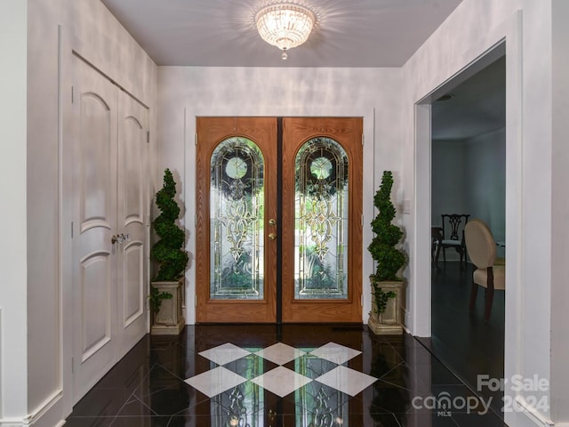 foyer entrance featuring dark tile patterned floors, a chandelier, and french doors