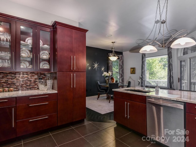 kitchen featuring dark brown cabinets, dark tile patterned floors, light stone counters, stainless steel dishwasher, and a sink