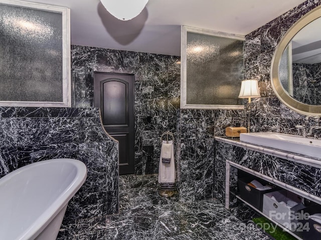 bathroom with a tub, vanity, and tile walls