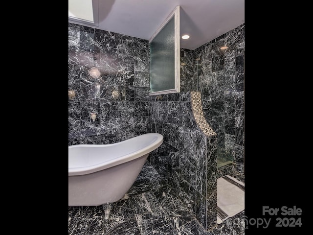 full bath with a soaking tub, marble finish floor, a walk in shower, and tile walls