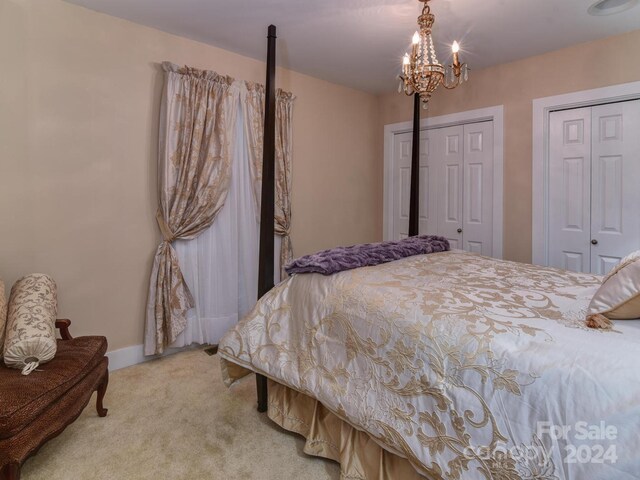 carpeted bedroom with a notable chandelier and two closets