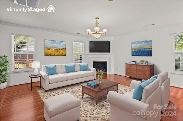 living room with ornamental molding, an inviting chandelier, and wood-type flooring