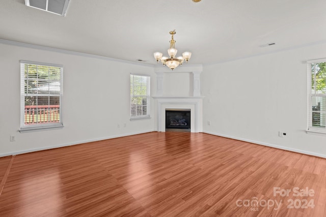 unfurnished living room with light wood-type flooring, ornamental molding, and a healthy amount of sunlight