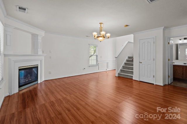 unfurnished living room featuring ornamental molding, hardwood / wood-style floors, and an inviting chandelier