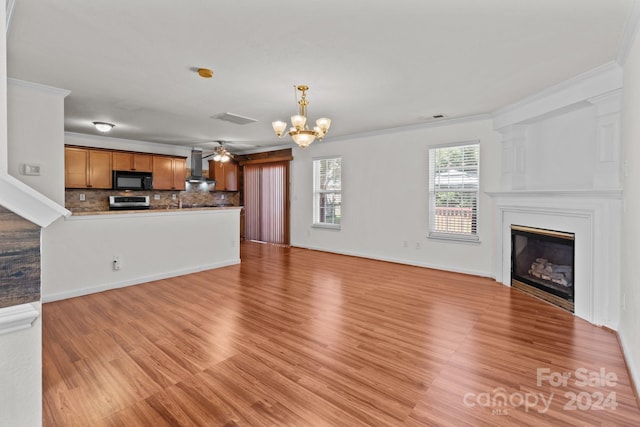 unfurnished living room with ornamental molding, light hardwood / wood-style flooring, and an inviting chandelier