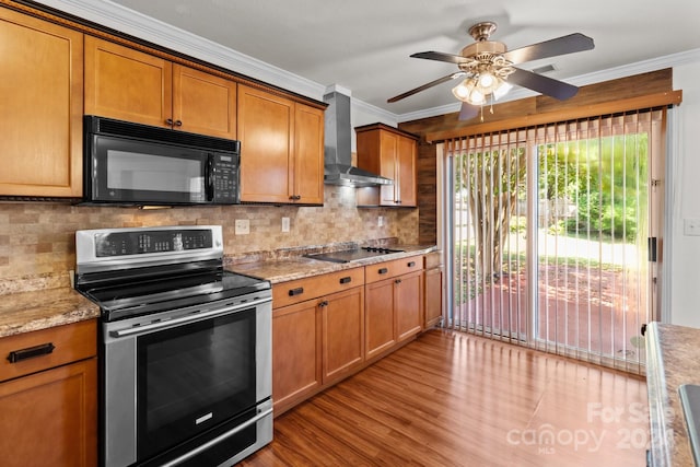 kitchen featuring crown molding, light wood-type flooring, black appliances, wall chimney exhaust hood, and ceiling fan