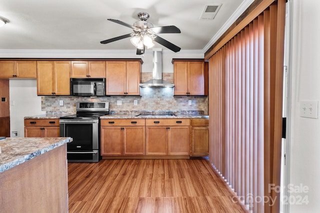 kitchen featuring ornamental molding, light hardwood / wood-style flooring, black appliances, ceiling fan, and wall chimney range hood