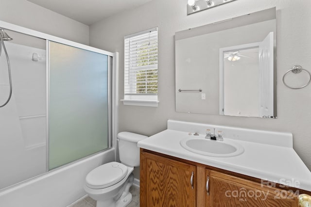 full bathroom with toilet, tile patterned floors, shower / bath combination with glass door, vanity, and ceiling fan