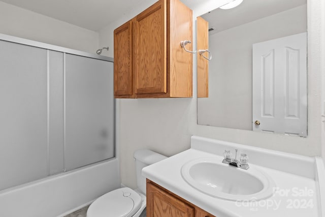 full bathroom featuring enclosed tub / shower combo, toilet, and vanity