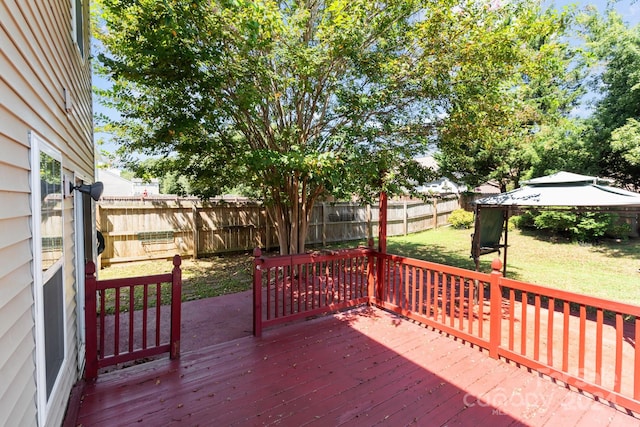 wooden terrace featuring a lawn and a gazebo