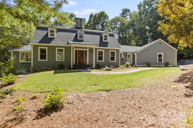 view of front facade with a shingled roof, a front yard, metal roof, and a chimney