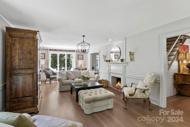 living room featuring hardwood / wood-style flooring, a notable chandelier, and ornamental molding