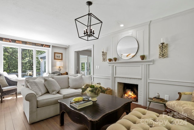 living room with a wealth of natural light, a fireplace, light hardwood / wood-style floors, and a notable chandelier