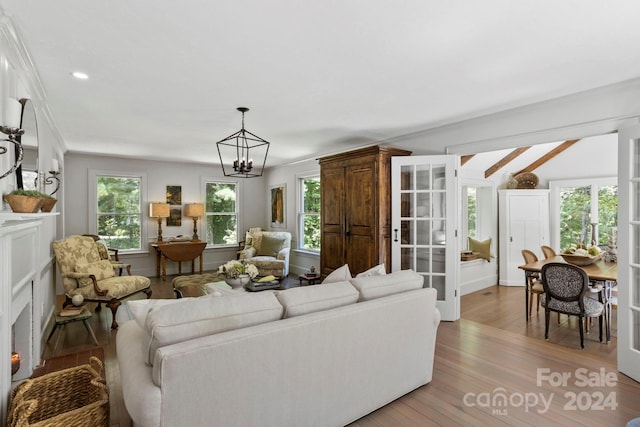 living room featuring ornamental molding, hardwood / wood-style flooring, a healthy amount of sunlight, and a notable chandelier