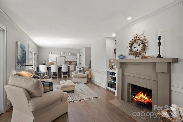 living room with ornamental molding, dark hardwood / wood-style flooring, and a brick fireplace