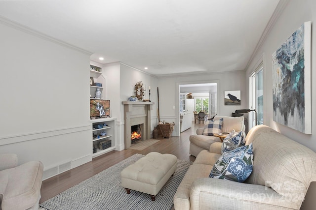 living room featuring ornamental molding, built in features, and wood-type flooring