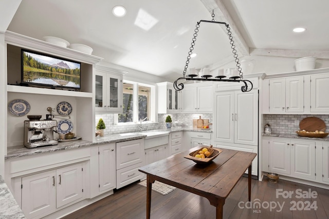 kitchen with white cabinets, beam ceiling, light stone countertops, and dark hardwood / wood-style floors