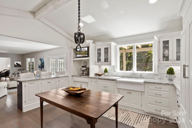 kitchen featuring dark hardwood / wood-style flooring, hanging light fixtures, kitchen peninsula, decorative backsplash, and white cabinetry