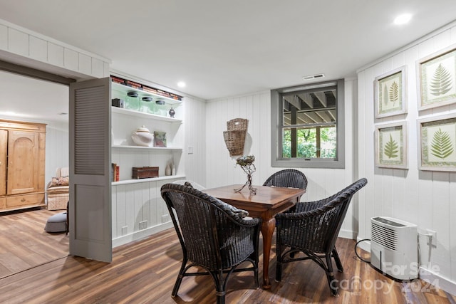 dining area featuring wood walls and dark hardwood / wood-style flooring