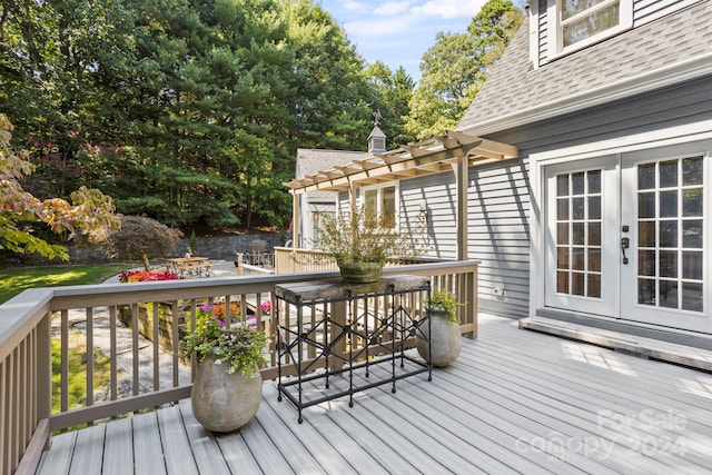 wooden deck with a pergola and french doors