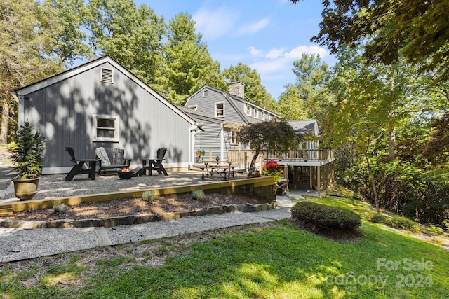 rear view of house with a yard, a fire pit, a patio area, and a deck