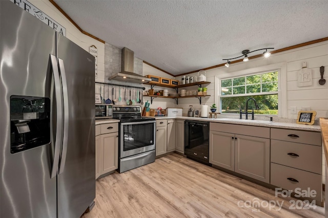 kitchen with stainless steel appliances, light hardwood / wood-style floors, sink, wall chimney range hood, and a textured ceiling