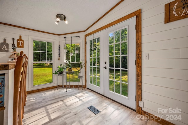 doorway to outside with vaulted ceiling, plenty of natural light, and light hardwood / wood-style flooring