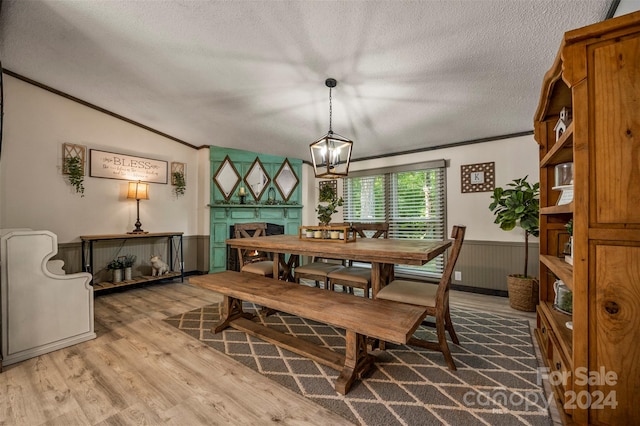 dining space featuring a textured ceiling, vaulted ceiling, hardwood / wood-style floors, crown molding, and a chandelier