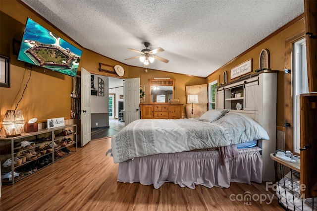 bedroom featuring lofted ceiling, ceiling fan, wood-type flooring, and a textured ceiling