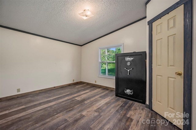 spare room featuring lofted ceiling, dark wood-type flooring, and a textured ceiling