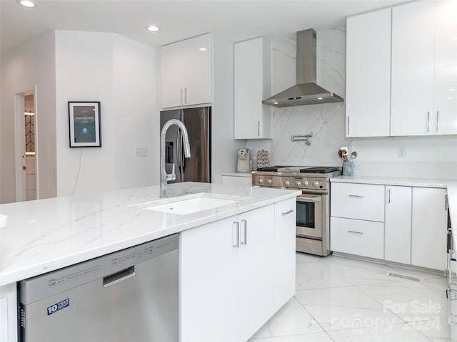 kitchen with appliances with stainless steel finishes, white cabinetry, light stone countertops, and wall chimney range hood