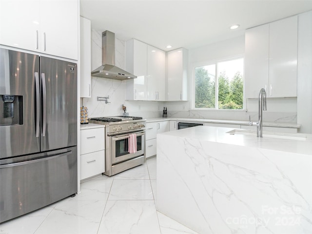 kitchen featuring sink, white cabinets, wall chimney exhaust hood, appliances with stainless steel finishes, and light stone countertops