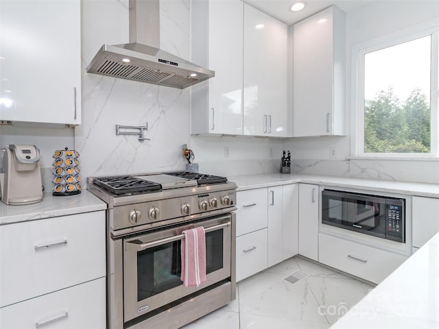 kitchen with black microwave, white cabinets, wall chimney range hood, double oven range, and light stone countertops