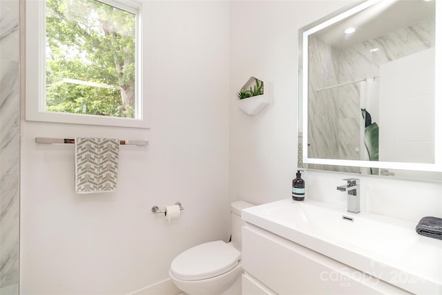 bathroom featuring a tile shower, vanity, and toilet